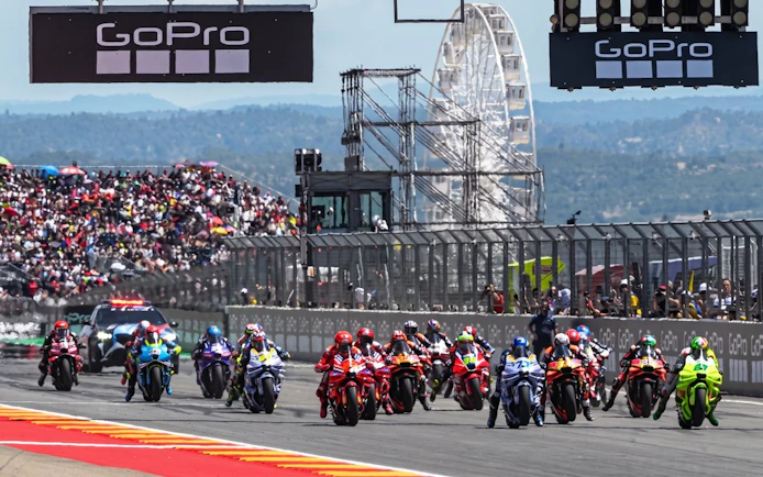 Motorcycles racing at MotoGP Mandalika Pertamina Grand Prix of Indonesia 2026 with a Ferris wheel in the background.