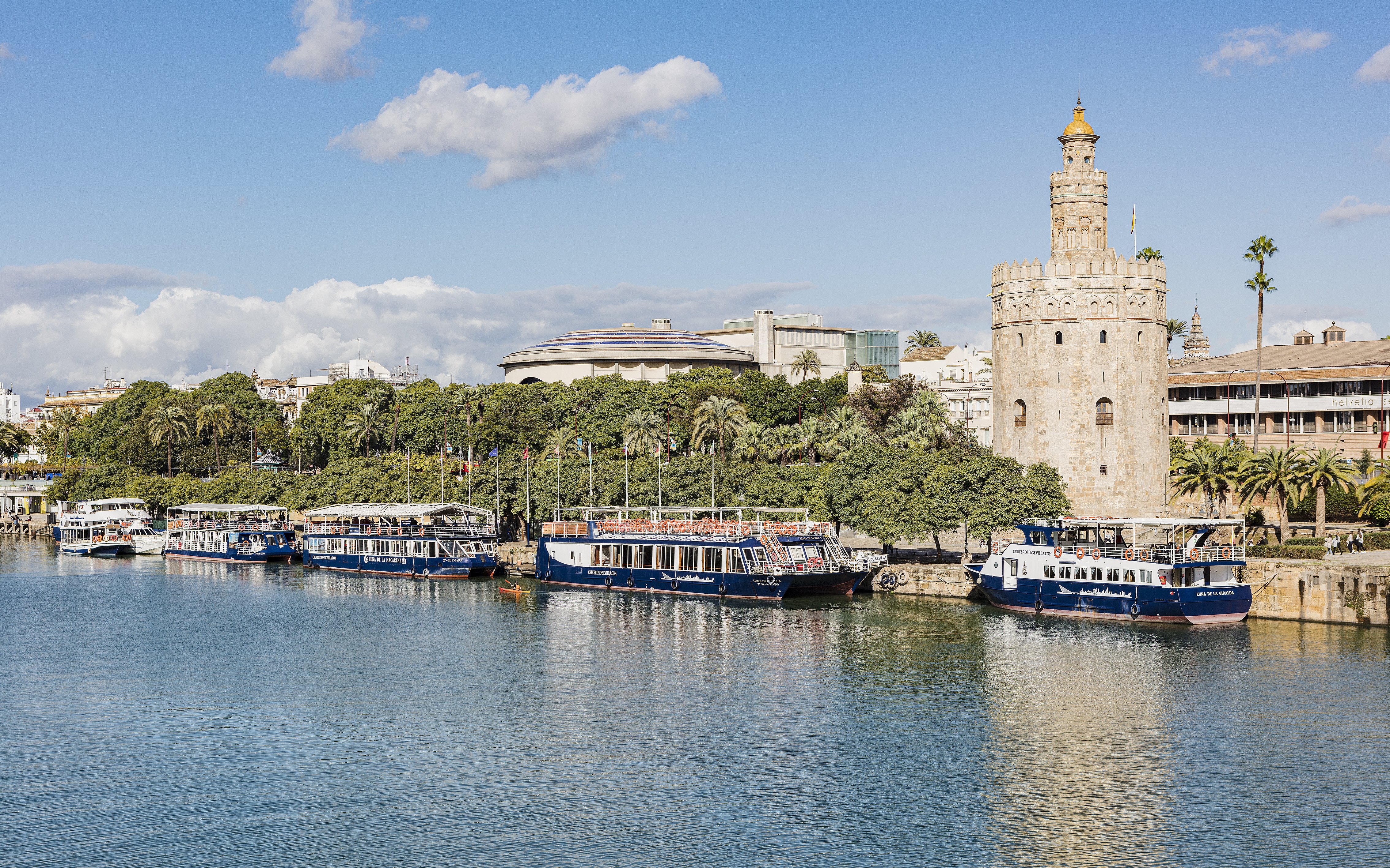 Cruise boats docked near Torre del Oro on the Guadalquivir River in Seville.
