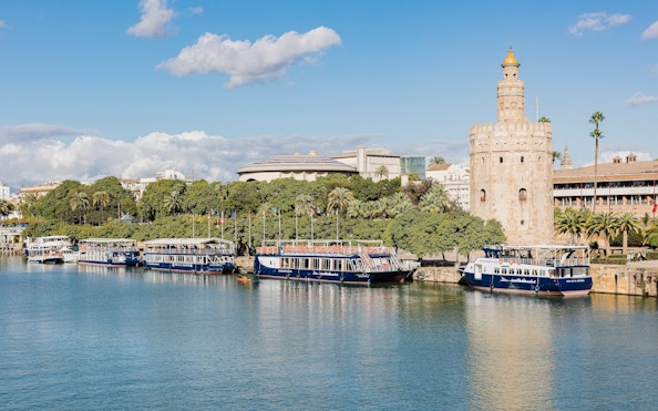 Cruise boats docked near Torre del Oro on the Guadalquivir River in Seville.
