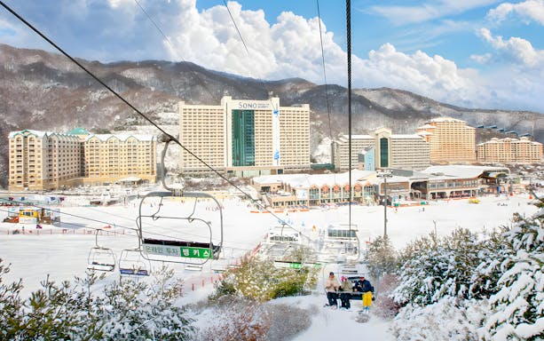 Ski lift at Vivaldi Park Snowy Land with snowy mountains and resort buildings in Seoul.