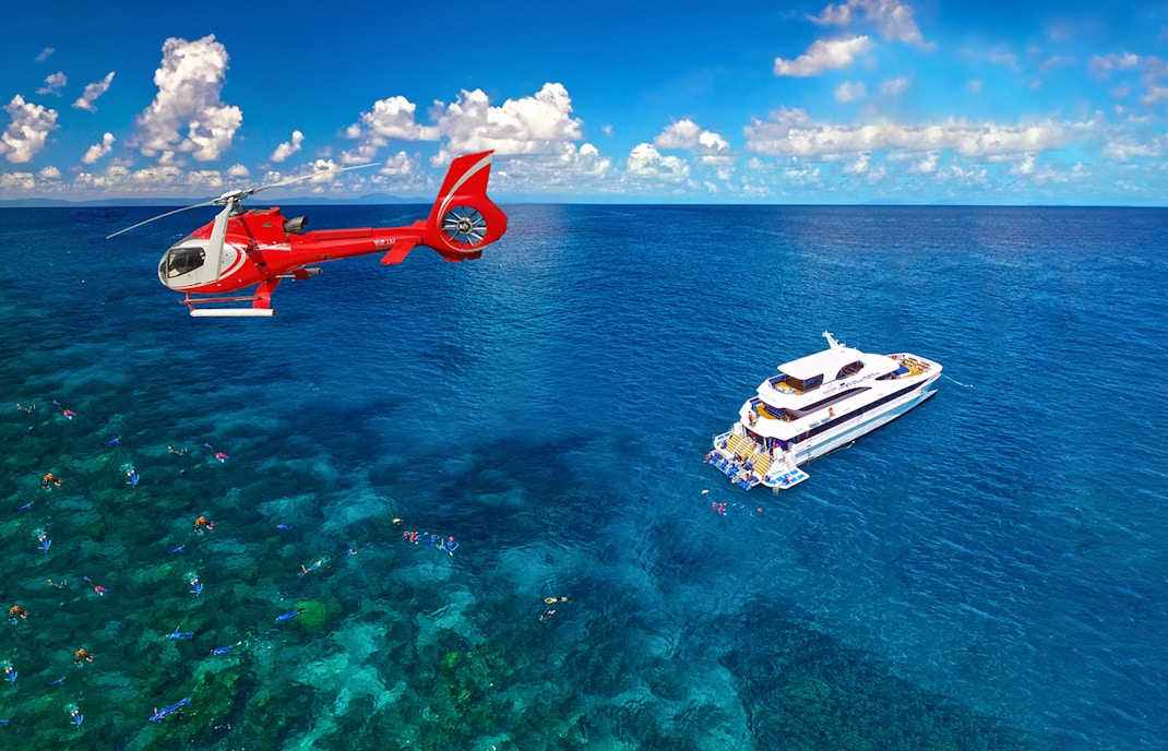 Helicopter flying over Great Barrier Reef with cruise ship below.