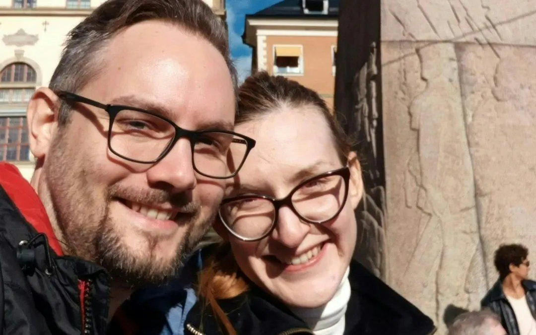 Couple smiling in front of a historic building in Stockholm during a self-guided city exploration game.
