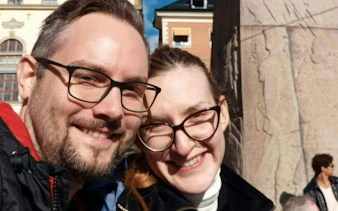 Couple smiling in front of a historic building in Stockholm during a self-guided city exploration game.