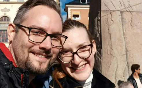 Couple smiling in front of a historic building in Stockholm during a self-guided city exploration game.