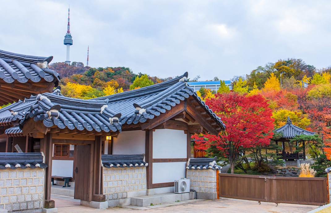 N Seoul Tower behind traditional Hanok Village with autumn foliage in Seoul, South Korea.