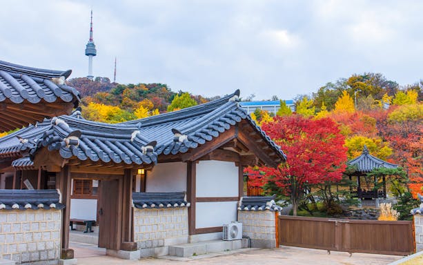 N Seoul Tower behind traditional Hanok Village with autumn foliage in Seoul, South Korea.