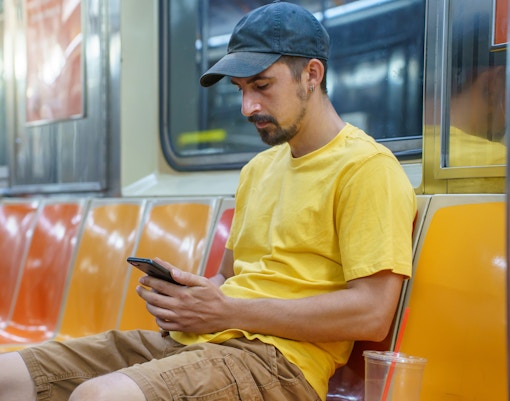 Man using phone on New York City subway.