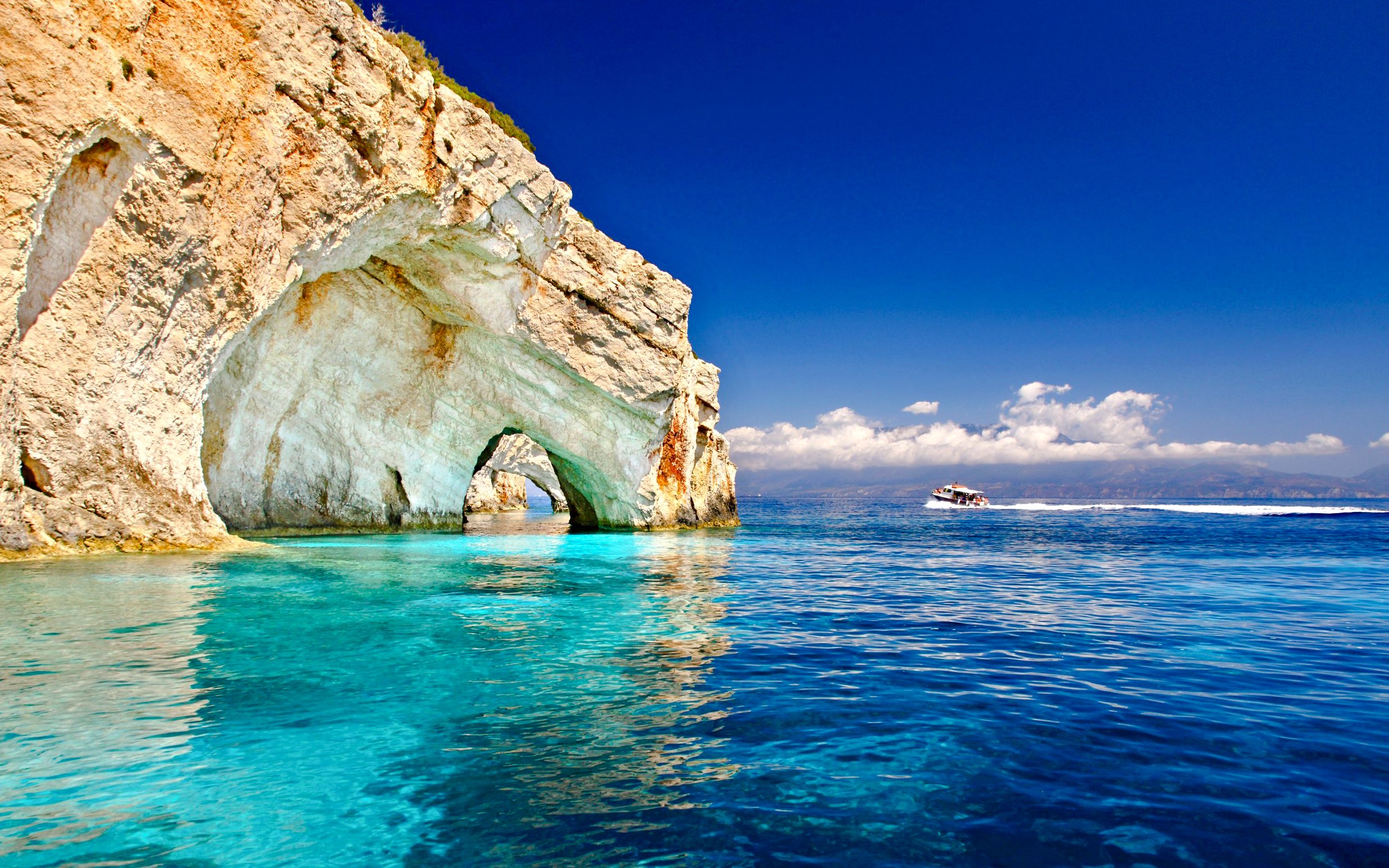 Boat cruising near limestone arches on Zante coast, Greece.