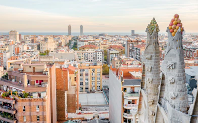 View of Barcelona from the Sagrada Familia's Nativity facade tower, showing cityscape and sea.