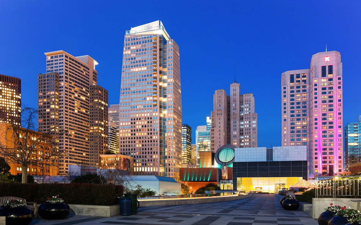 San Francisco Museum of Modern Art with city skyline at dusk.
