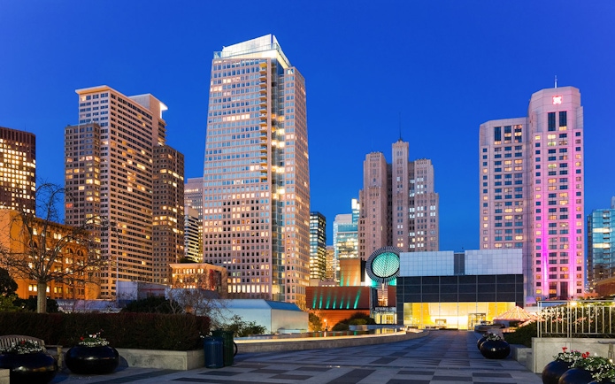 San Francisco Museum of Modern Art with city skyline at dusk.