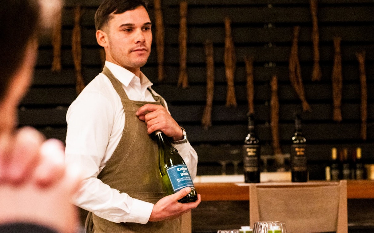 Server presenting wine at Viña Concha y Toro nighttime dinner show.