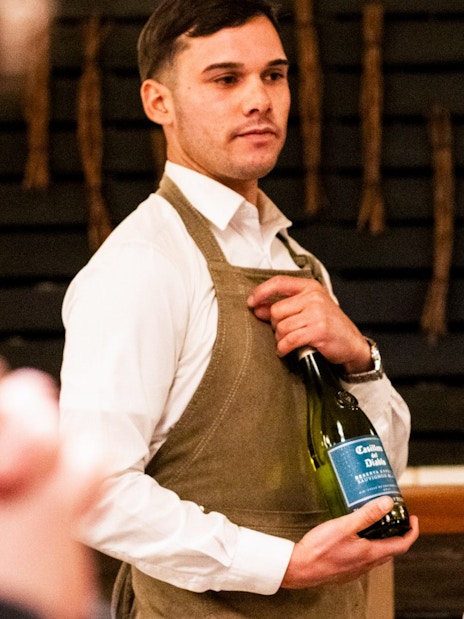 Server presenting wine at Viña Concha y Toro nighttime dinner show.