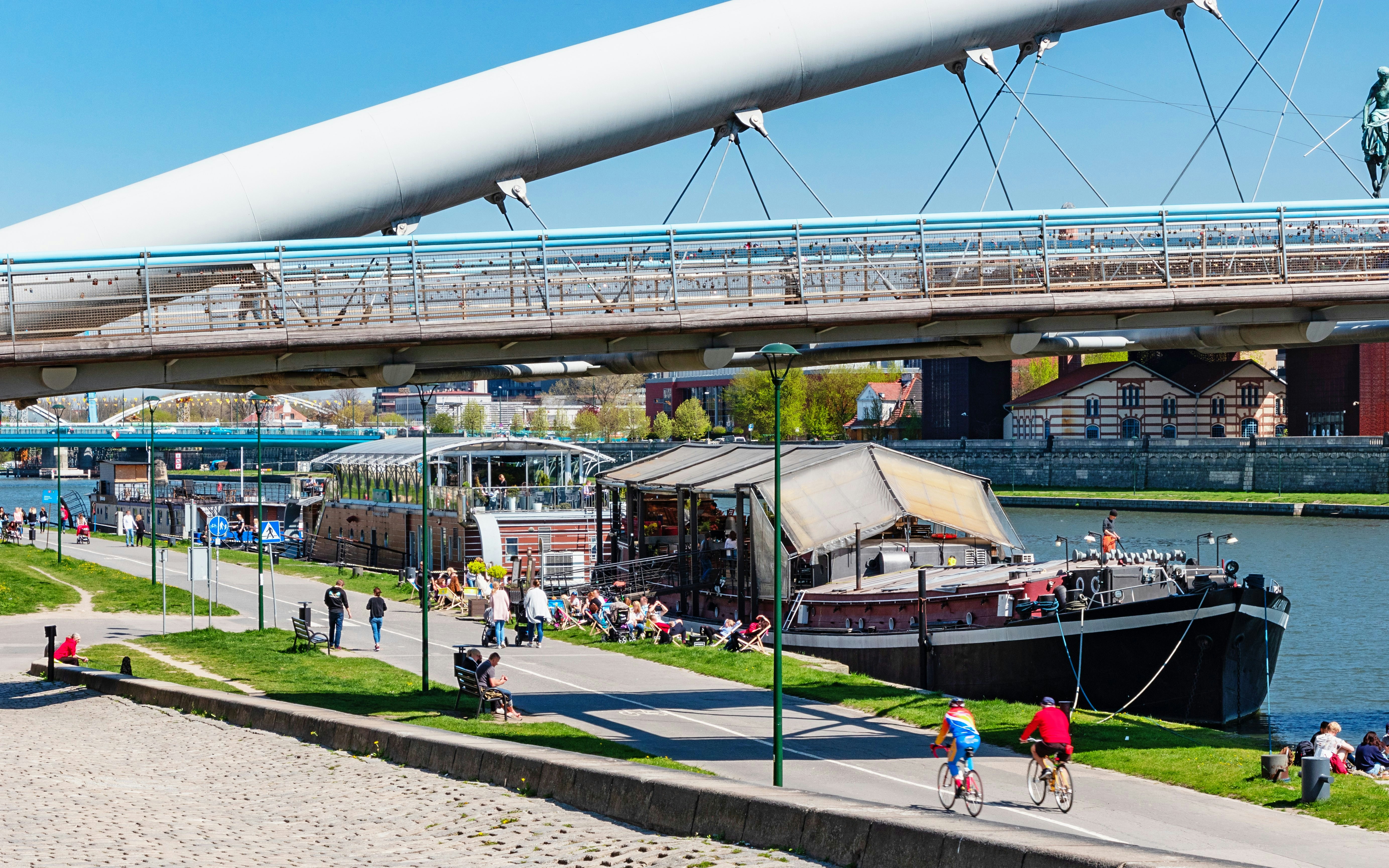 Cyclists and pedestrians on Vistula Boulevards near Bernatka footbridge in Krakow.