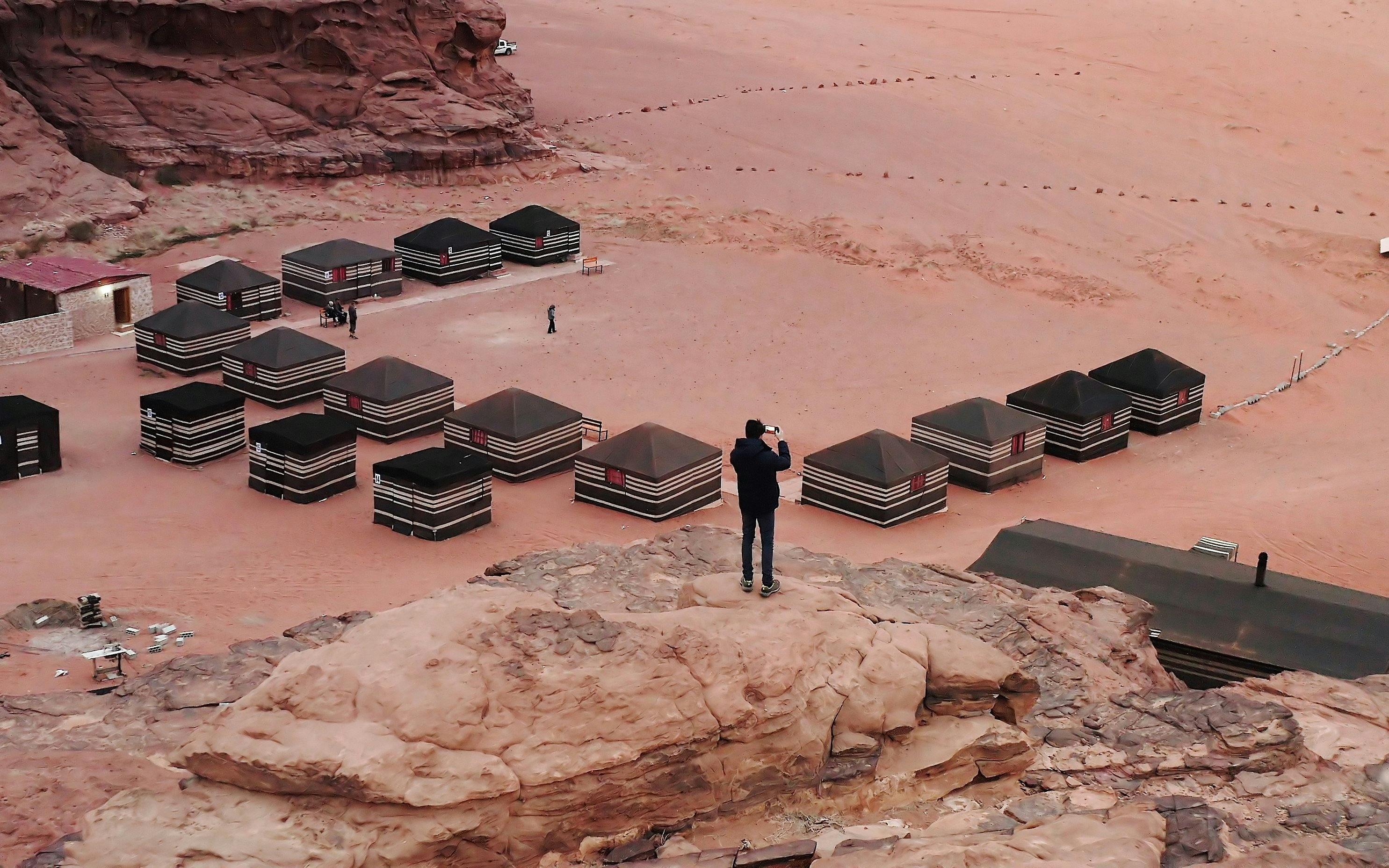 Bedouin camp tents in Wadi Rum desert, Jordan, with a person taking photos.