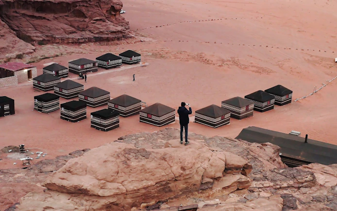 Bedouin camp tents in Wadi Rum desert, Jordan, with a person taking photos.