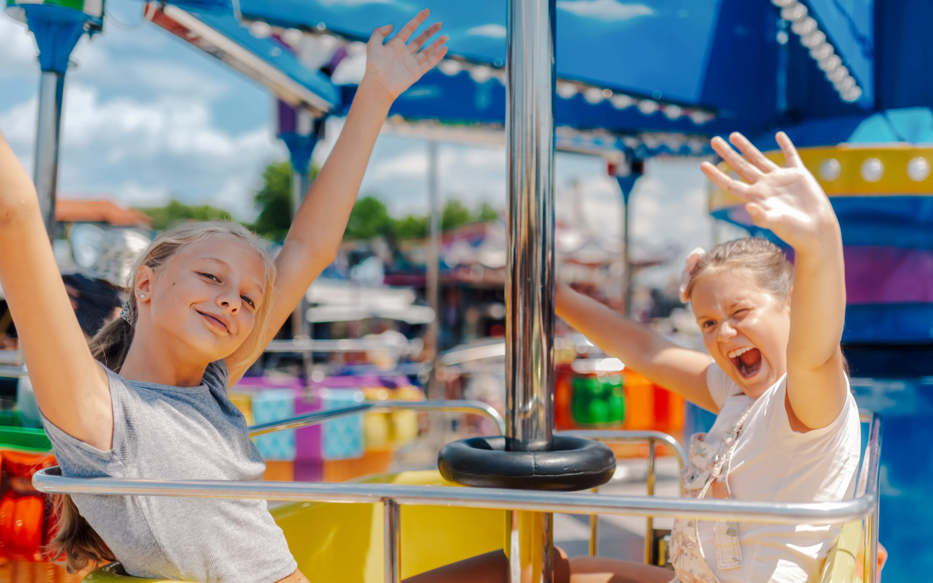 Two girls enjoying a carousel ride at an amusement park.