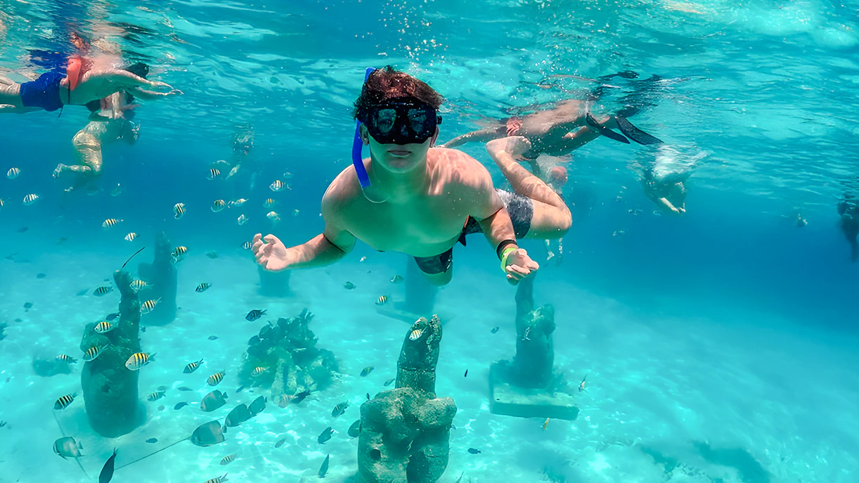 Snorkelers exploring underwater sculptures and fish in Isla Mujeres.