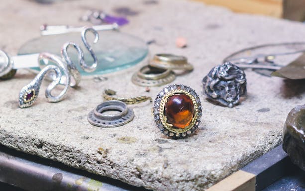 Artisan jewelry pieces on a workbench in Ortigia shop.