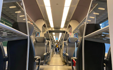 Interior view of Malpensa Express train with empty seats and overhead luggage racks.