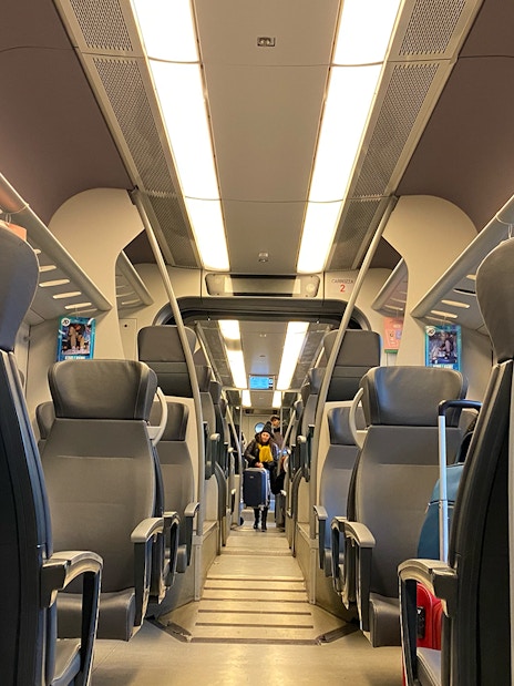 Interior view of Malpensa Express train with empty seats and overhead luggage racks.