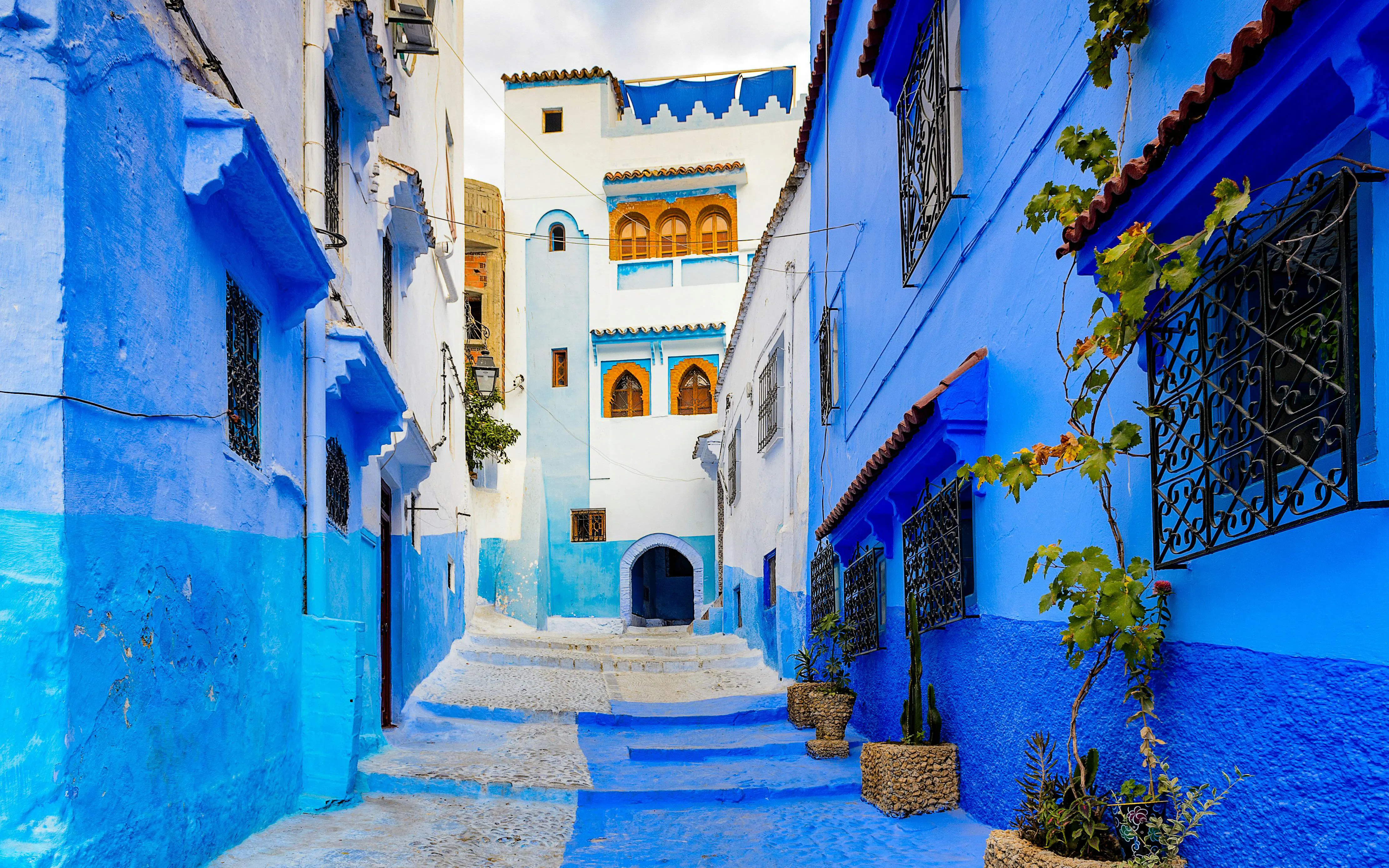 Narrow blue alley with traditional buildings in Chefchaouen, Morocco.