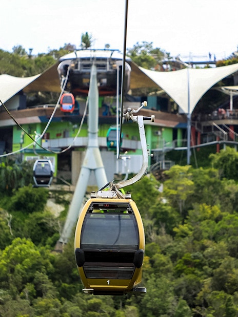 Langkawi SkyCab cable cars ascending over lush greenery towards the station.