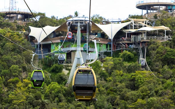 Langkawi SkyCab cable cars ascending over lush greenery towards the station.