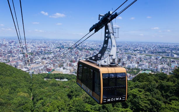 Mt. Moiwa ropeway car ascending over Sapporo cityscape, Japan.