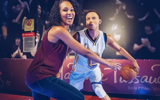 Person posing with a basketball player wax figure at Madame Tussauds San Francisco.
