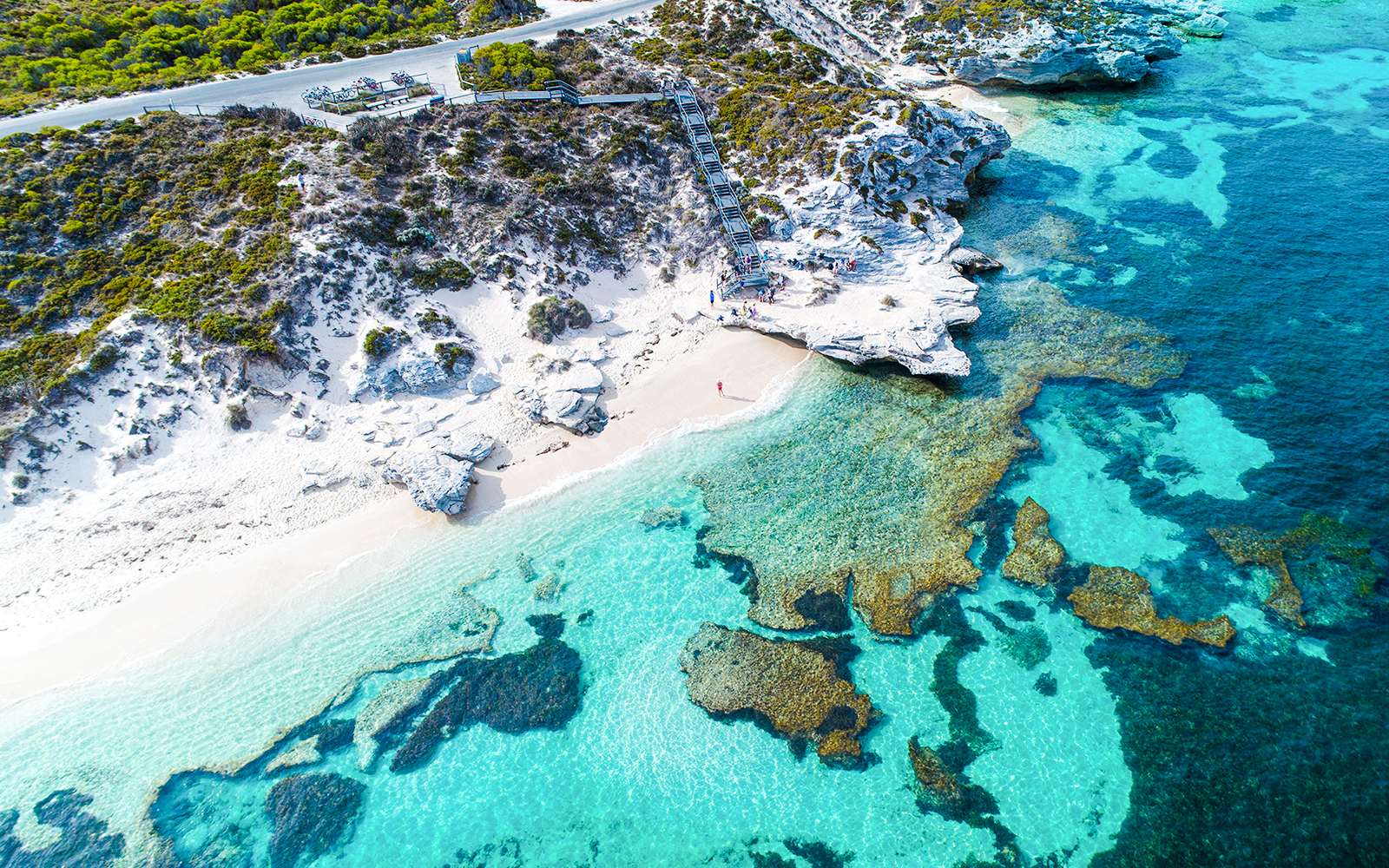 Aerial view of Rottnest Island's coastline with clear turquoise waters and rocky shoreline.