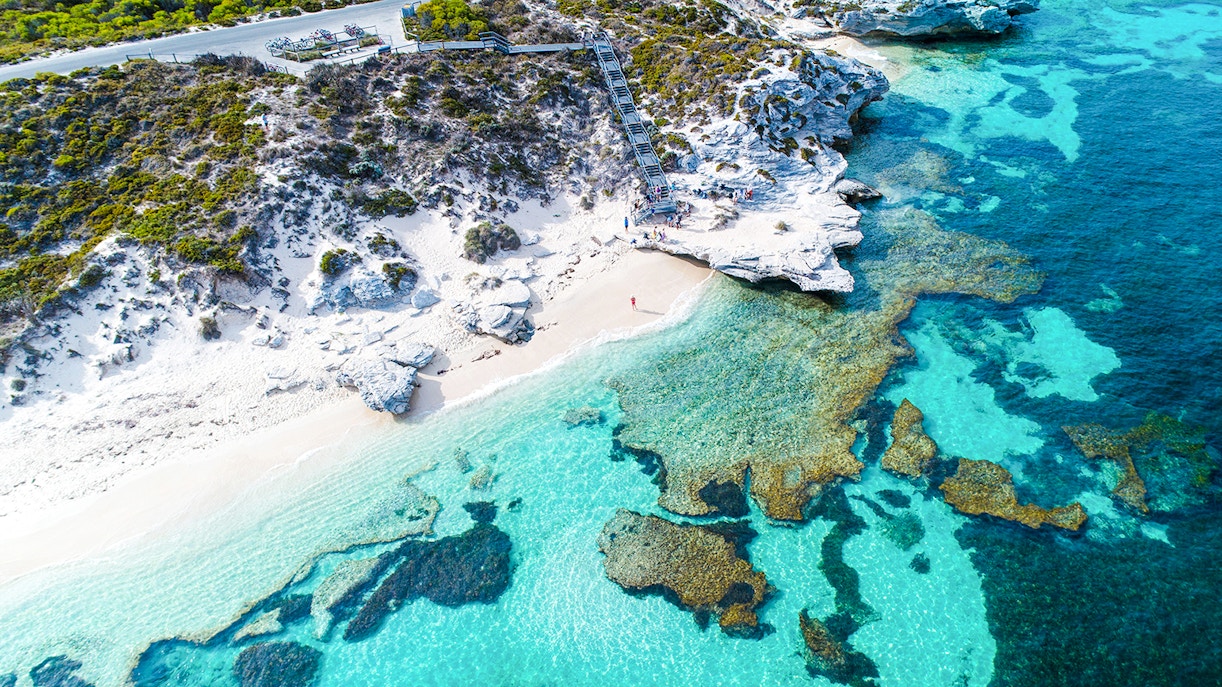 Aerial view of Rottnest Island's coastline with clear turquoise waters and rocky shoreline.