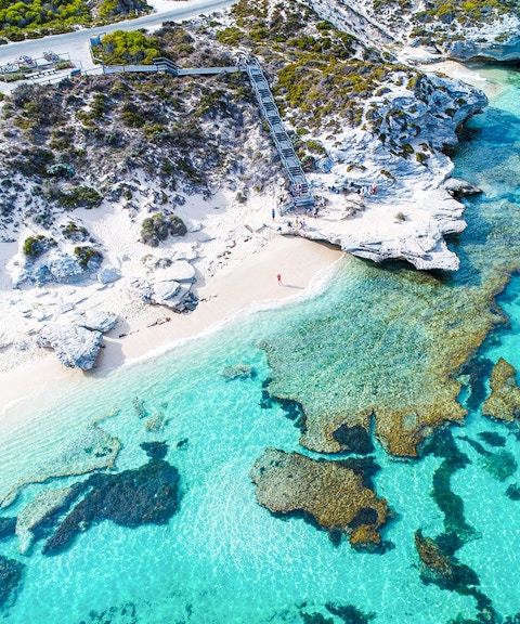 Aerial view of Rottnest Island's coastline with clear turquoise waters and rocky shoreline.
