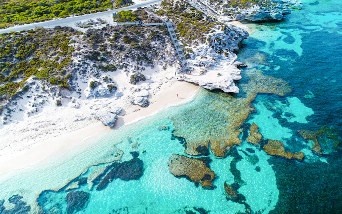 Aerial view of Rottnest Island's coastline with clear turquoise waters and rocky shoreline.