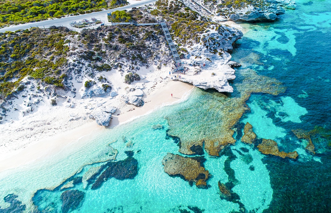 Aerial view of Rottnest Island's coastline with clear turquoise waters and rocky shoreline.