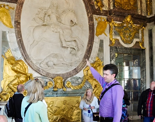 Tour guide explaining history inside Versailles Palace, France.
