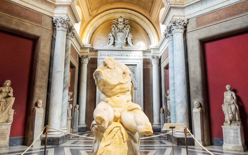 Vatican Museums sculpture hall with ancient statues and marble columns.