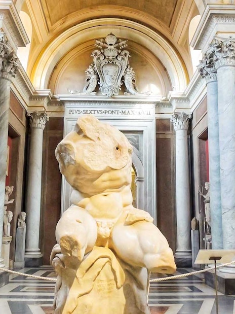 Vatican Museums sculpture hall with ancient statues and marble columns.