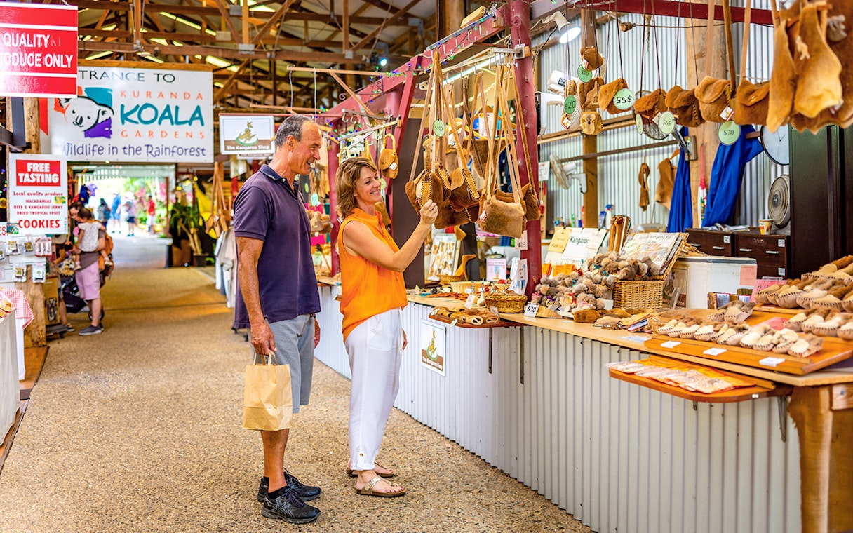 Couple shopping for local crafts at Kuranda markets on a tour from Cairns.