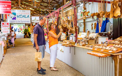 Couple shopping for local crafts at Kuranda markets on a tour from Cairns.