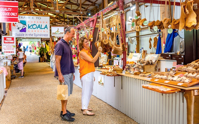 Couple shopping for local crafts at Kuranda markets on a tour from Cairns.