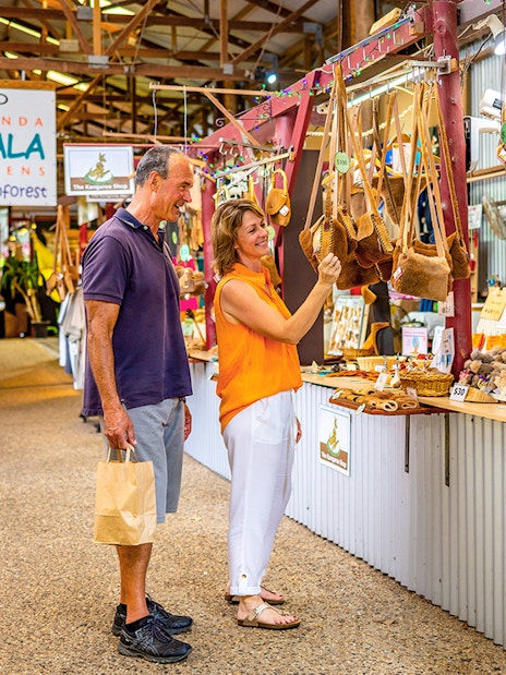 Couple shopping for local crafts at Kuranda markets on a tour from Cairns.