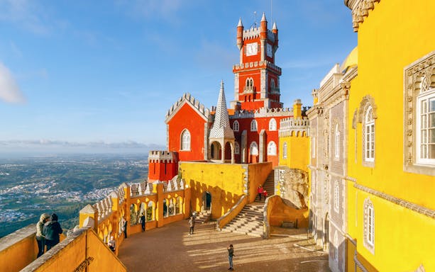 Terrace view of Pena National Palace, Sintra, with colorful architecture and distant landscape.