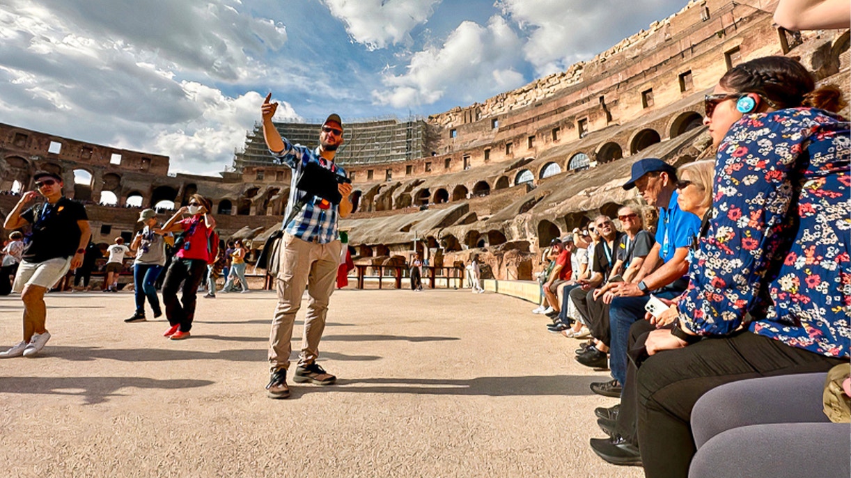 Tour guide leading a group inside the Colosseum in Rome with arena access.