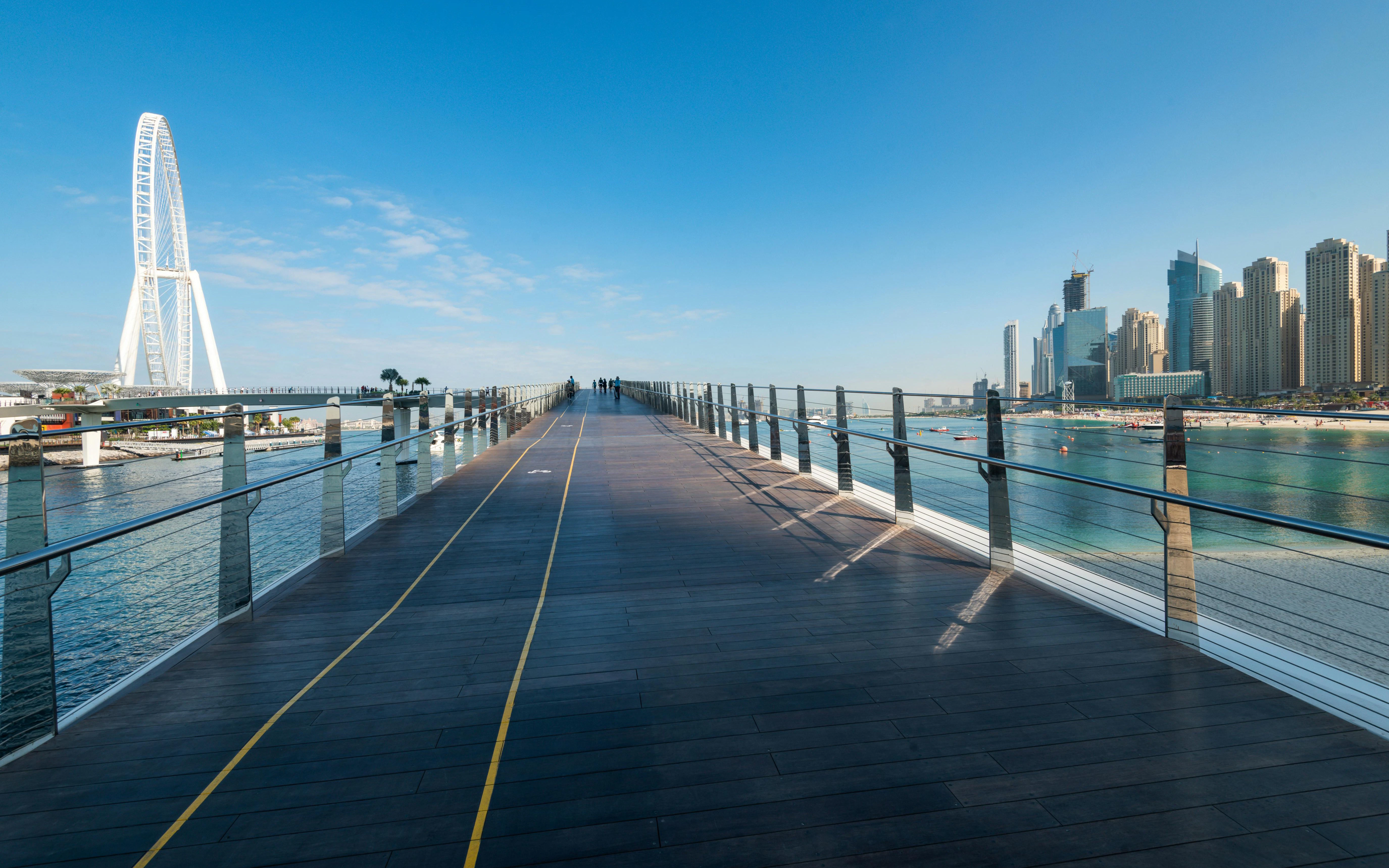 Pedestrian bridge leading to Bluewaters Island with Dubai Ain in the background.