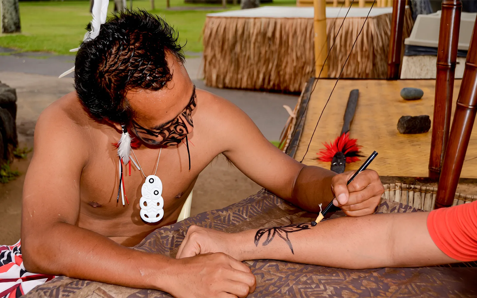 Tattoo artist creating traditional design at Voyagers of the Pacific Luau.