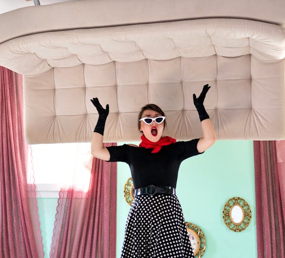 Person in vintage attire inside Upside Down House Melaka with furniture on ceiling.