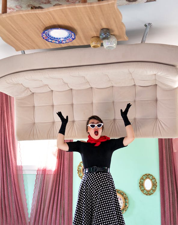 Person in vintage attire inside Upside Down House Melaka with furniture on ceiling.