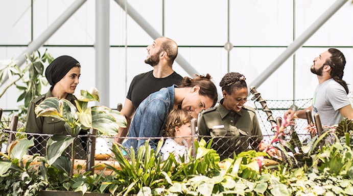 Visitors exploring lush greenery at The Green Planet indoor rainforest.