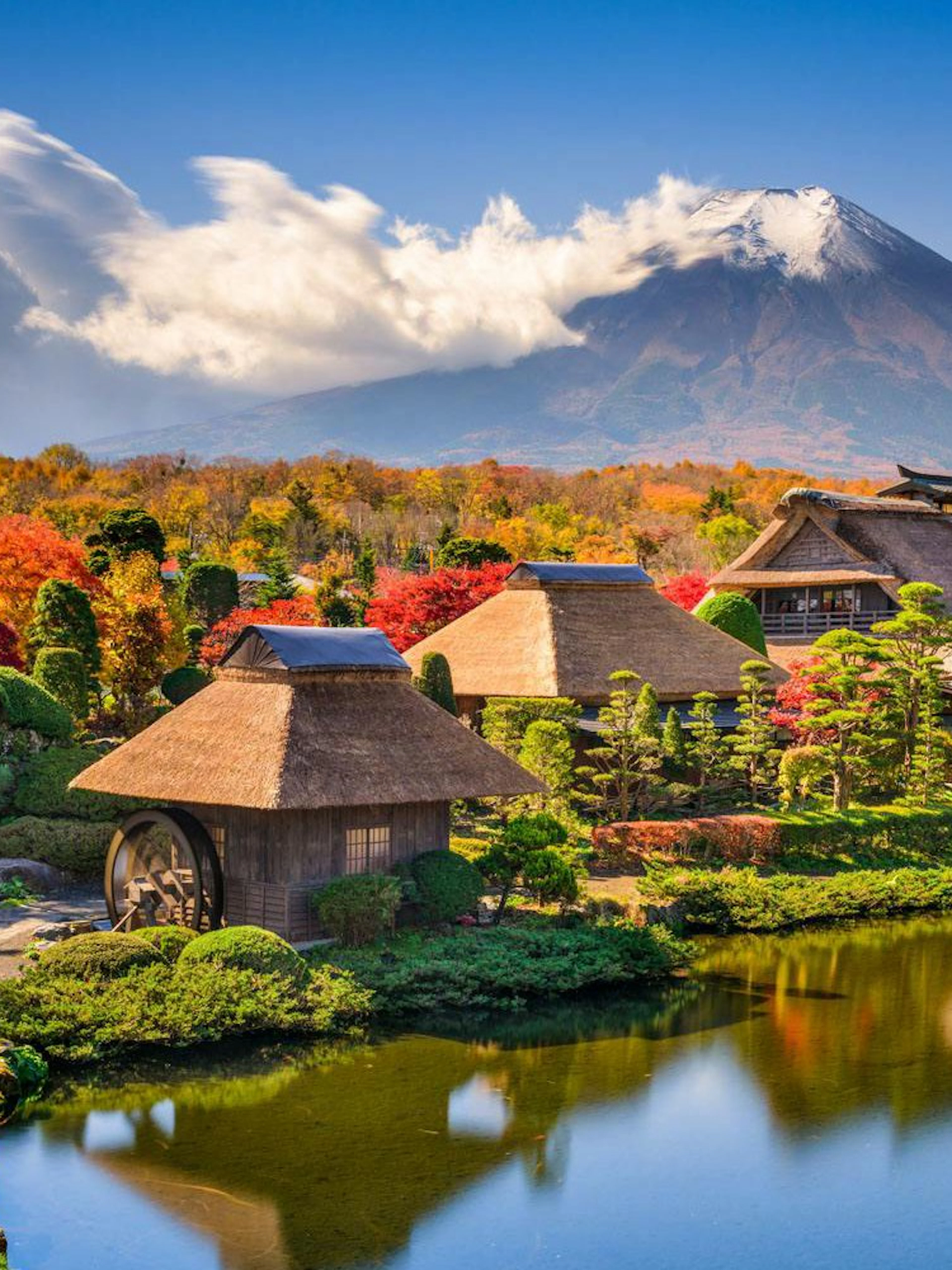 Traditional village with thatched roofs and pond, Mt. Fuji in background, Oshino Hakkai, Japan.